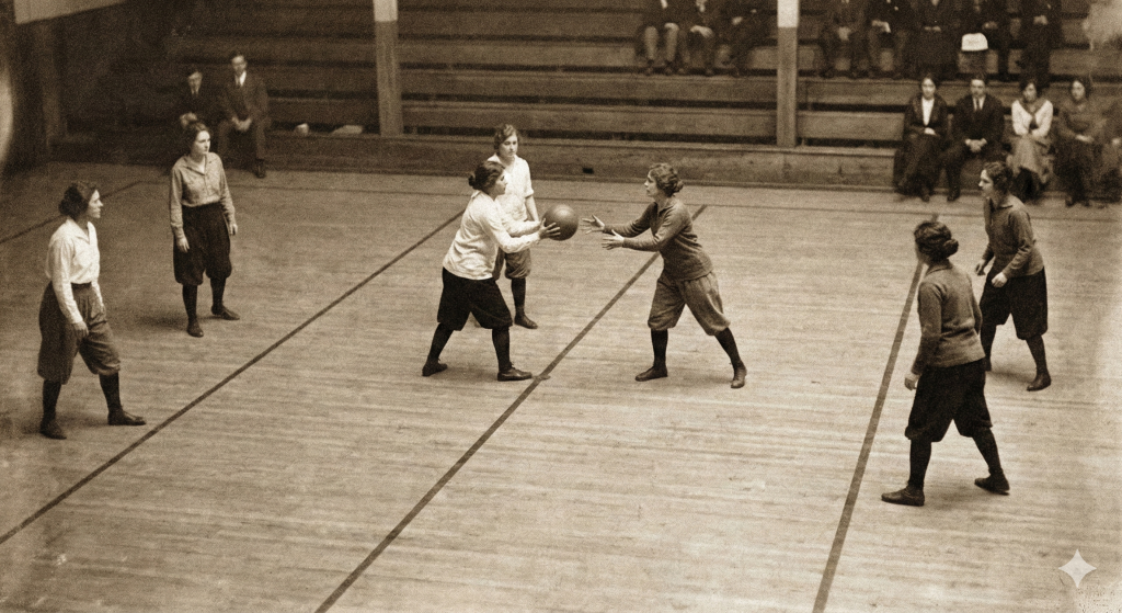 Recreación histórica de un partido de baloncesto femenino de principios del siglo XX jugando bajo las reglas de 6 contra 6 y división de tres zonas en pista de madera.