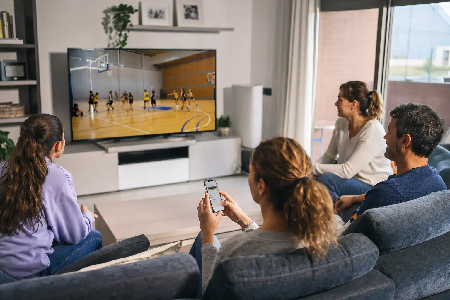 Familia viendo un partido de baloncesto retransmitido en directo desde casa